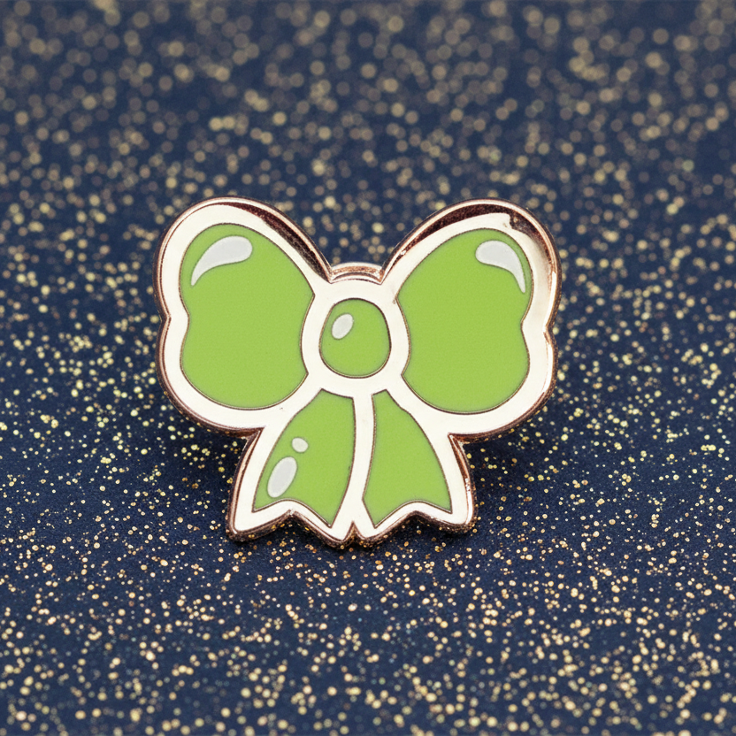 Green bow-shaped pin on a pink and gray background