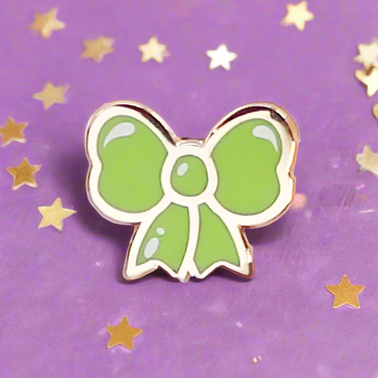 Green bow-shaped pin on a purple background with gold stars