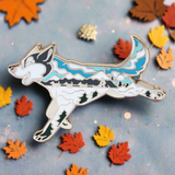 A gold metal enamel pin shaped like a husky dog with a blue and white color scheme on a two-tone background.