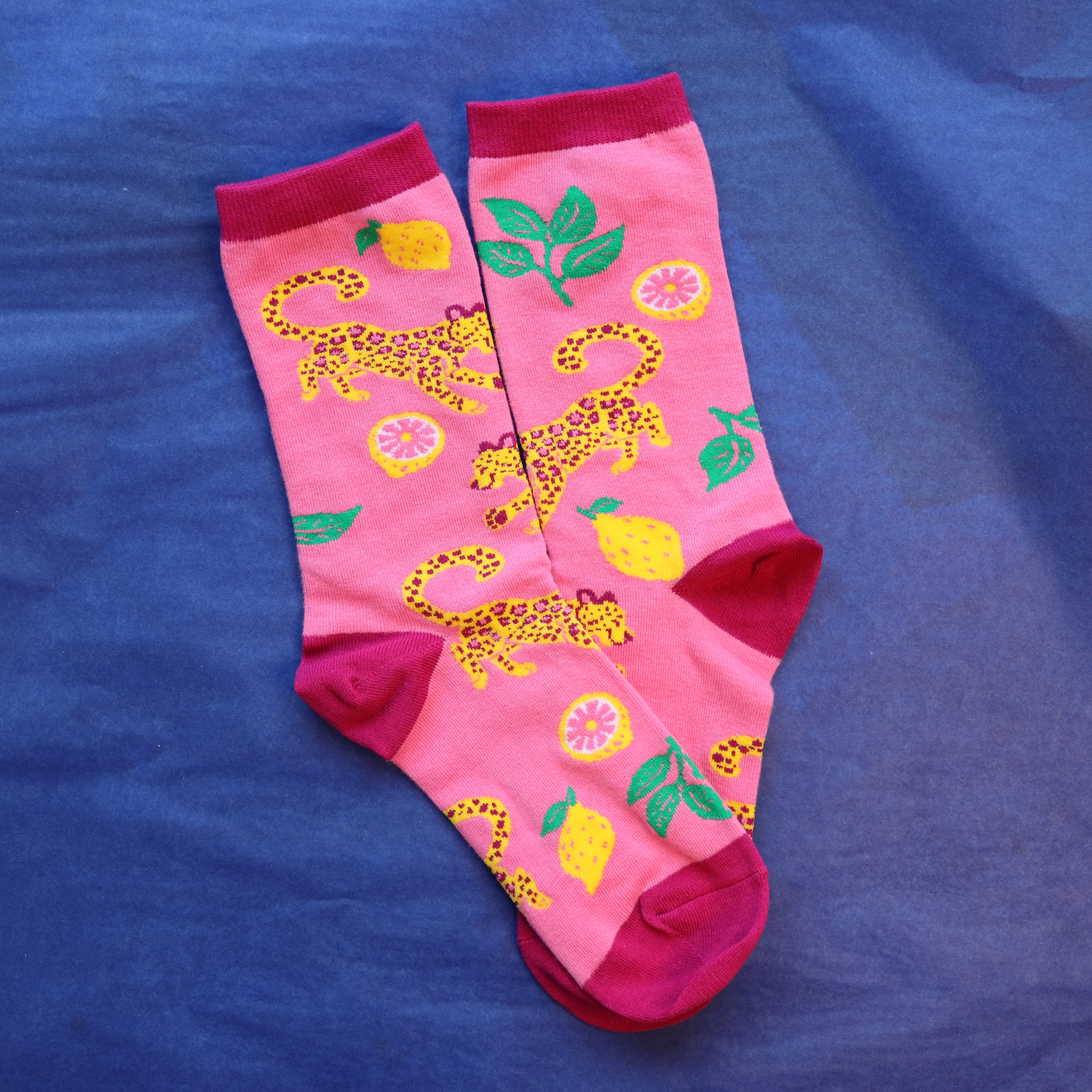 Pink socks with leopard and lemon design on a blue background