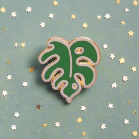 Green leaf-shaped pin on a pink and gray background
