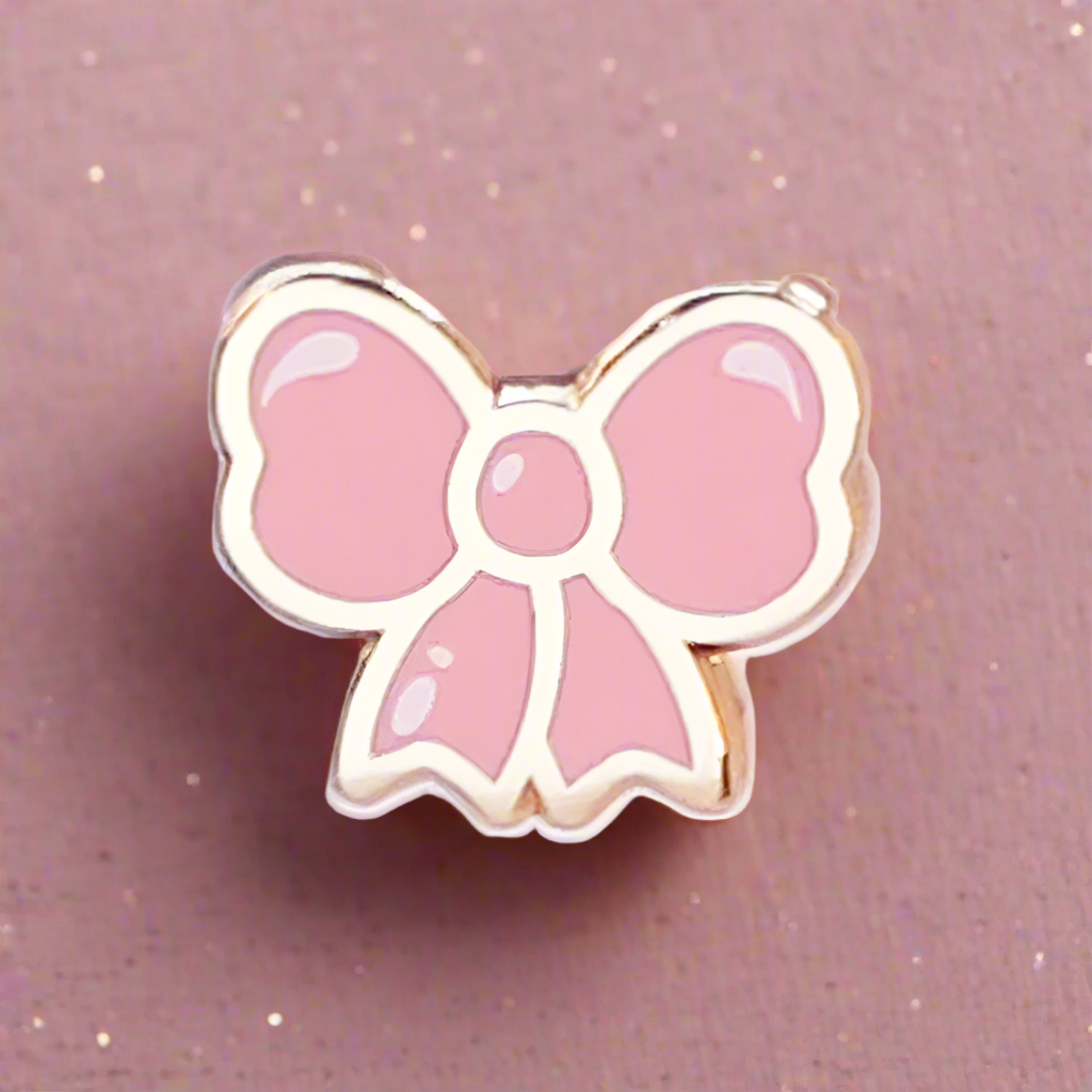 Pink bow-shaped pin on a pink background