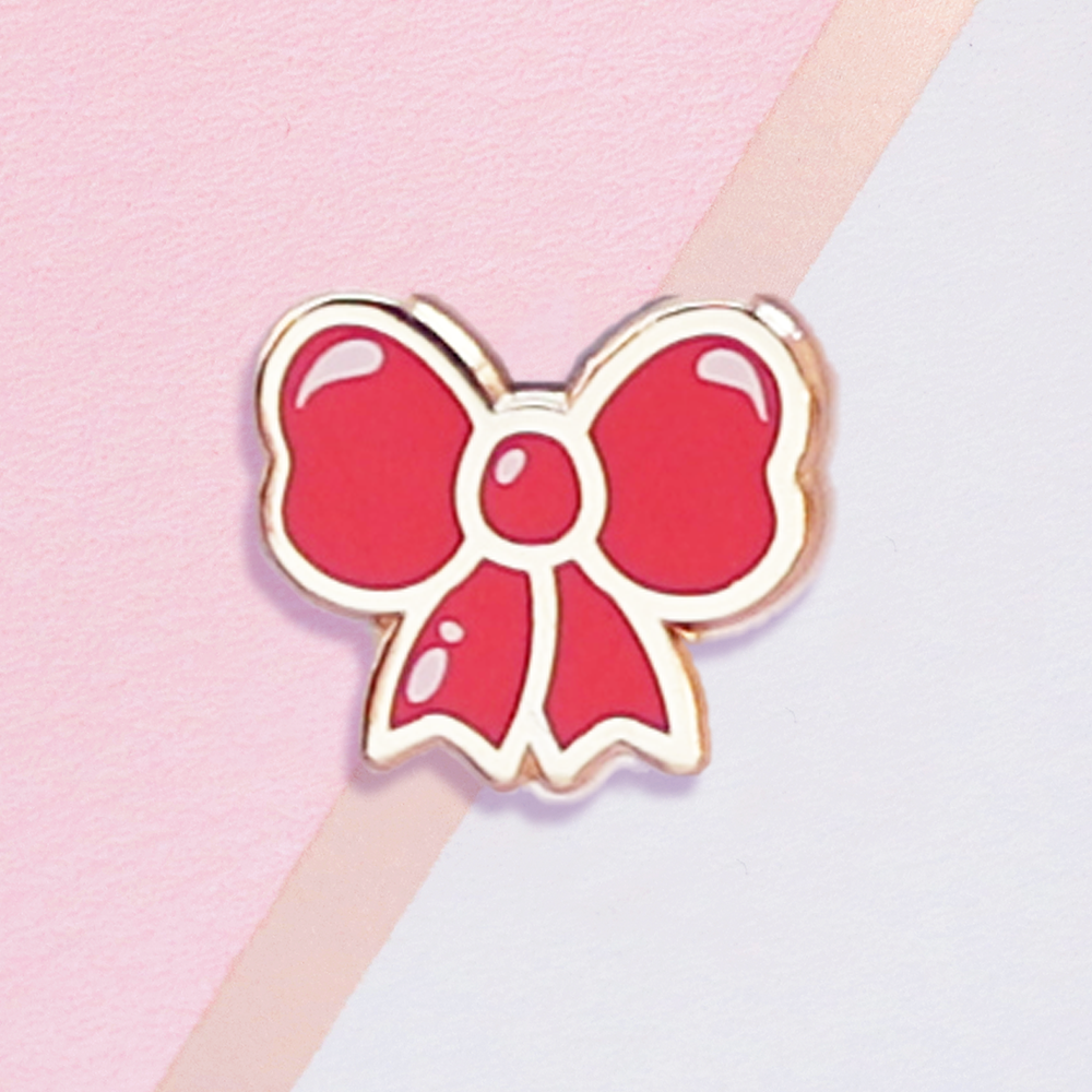 Red bow-shaped pin on a pink and white background