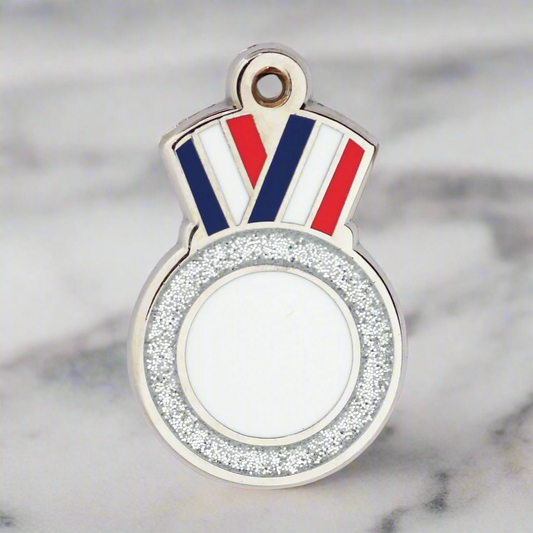 A silver medal charm with a red, white, and blue striped ribbon design at the top and a blank face in the center for personalization.