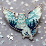 A silver metal enamel pin with a mythological creature, a griffin, depicted against a sky and forest background.