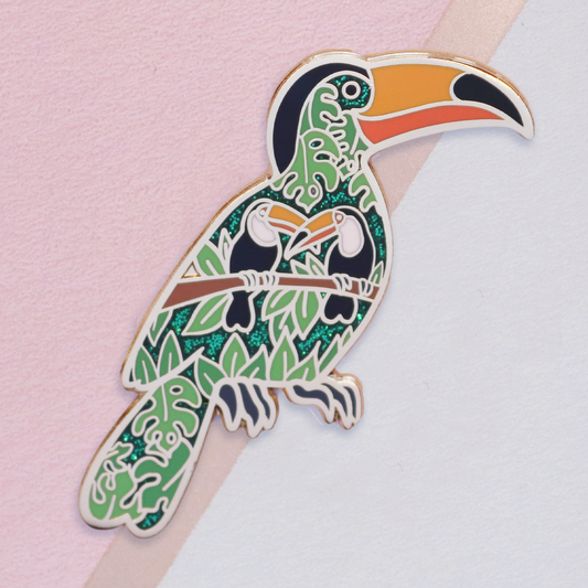 Colorful toucan-shaped pin on a pink and white background
