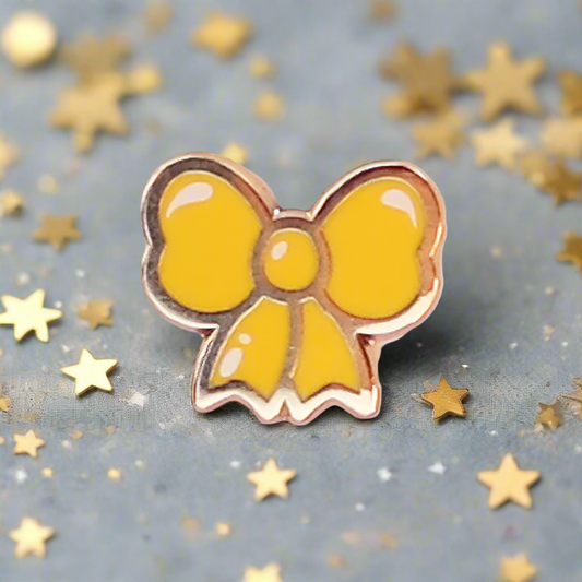 Yellow bow-shaped pin on a pink and white background